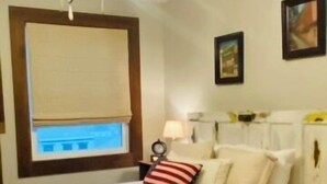 Een hotelkamer met een bed, nachtkastje, lamp en raam met blind.