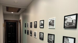 A hallway with framed black and white photographs on the wall, a wooden floor, and a door at the end. - The Madison Inn, Historic woodside view suite 205, Historic woodside view suite 205 (Madison)