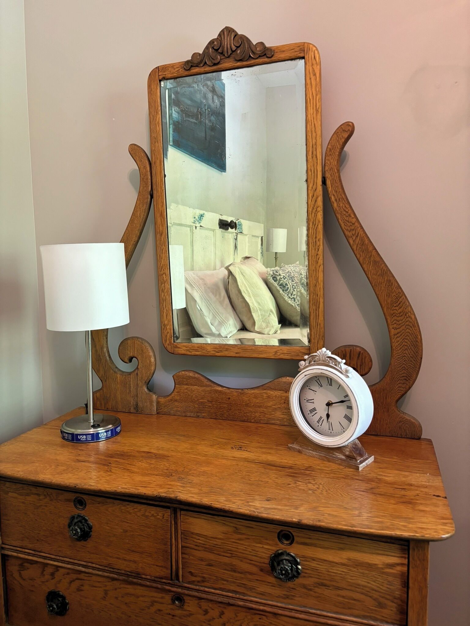 Un aparador de madera con un espejo, una lámpara y un reloj.