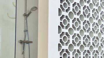 Une salle de bain avec une douche et un mur décoratif orné d’un motif géométrique.