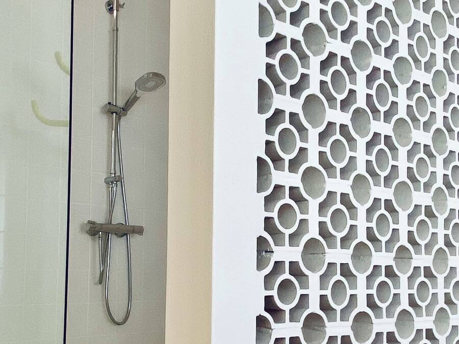 Une salle de bain avec une douche et un mur décoratif orné d’un motif géométrique.