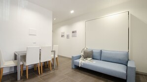 Ein modernes Zimmer mit Esstisch und Stühlen, einem blauen Sofa und einer Tafel an der Wand.