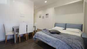 Ein Schlafzimmer mit Bett, Nachttisch und Schreibtisch mit Stühlen.
