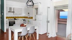 A modern kitchen with white cabinets, a checkered backsplash, and a dining area with a table and chairs.