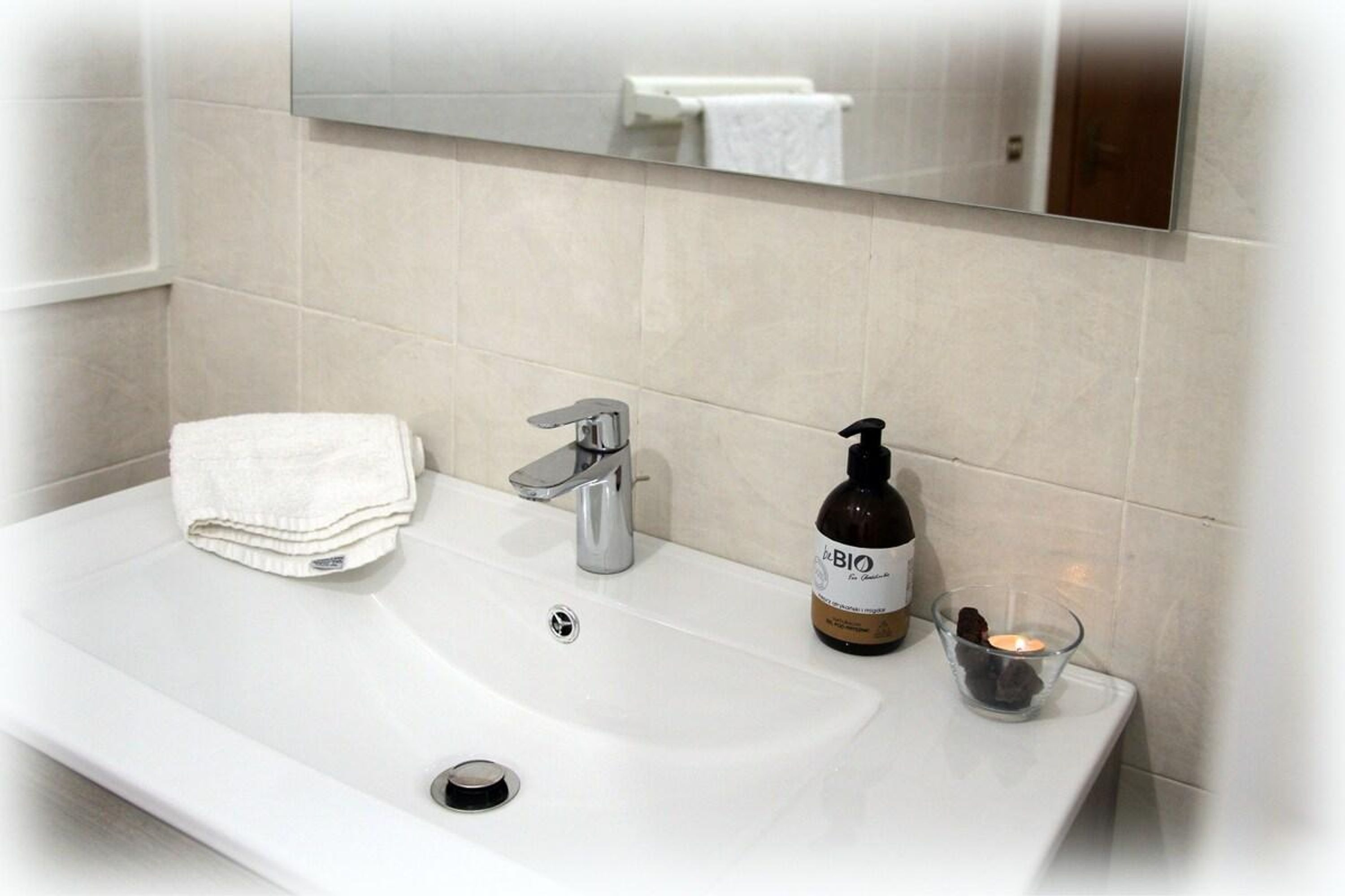 A bathroom with a white sink, a mirror above it, and a bottle of hand soap.