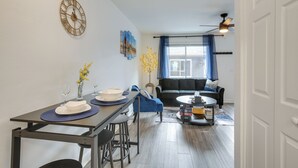 A modern living room with a sofa, a coffee table, and a dining area with a table set for two. - Dayton Condo w/ Courtyard < 3 to Downtown! (Dayton)