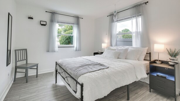 A bedroom with a bed, a chair, two bedside tables, and a window with curtains. - Dayton Condo w/ Courtyard < 3 to Downtown! (Dayton)