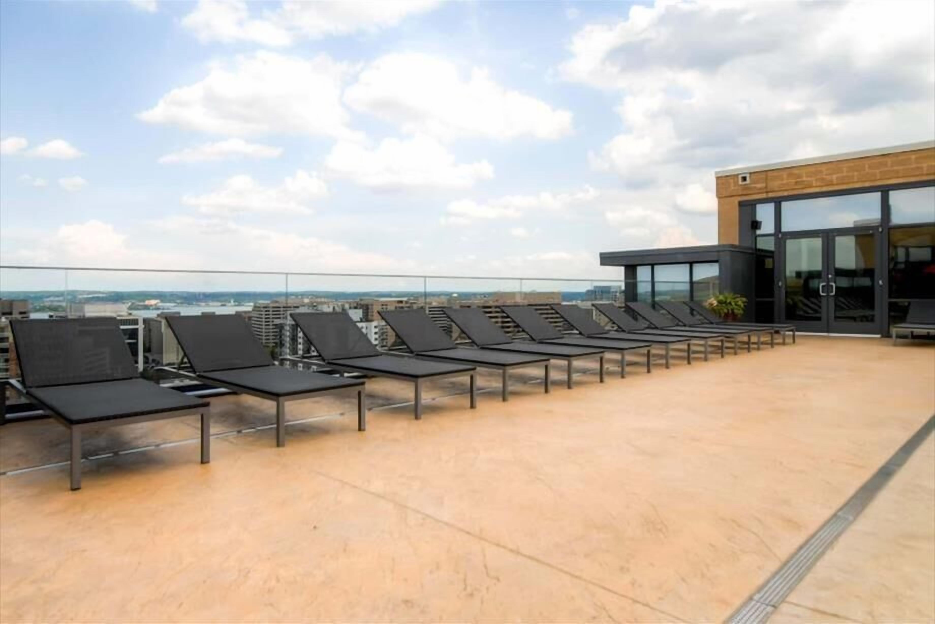 A rooftop terrace with sun loungers and a view of the cityscape.