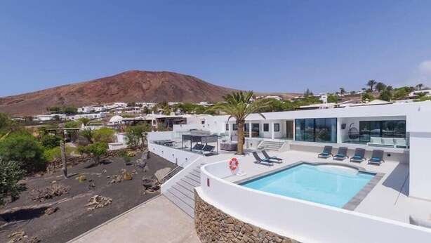 Un bâtiment moderne doté d’une piscine, d’une bouée de sauvetage et avec une montagne en arrière-plan.