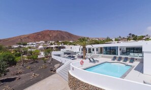 A modern building with a pool, a lifebuoy, and a mountain in the background.