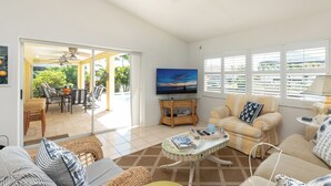 A living room with a sofa, armchairs, a coffee table, a TV, and a view of the outdoors.