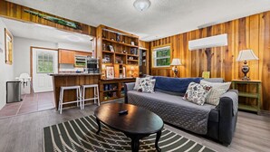 A cozy living room with a sofa, coffee table, and a bookshelf filled with books and decorations. - Charming Serene Cabin in Nantahala Gorge near Bryson City (Bryson City)