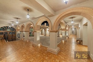 Un ambiente spazioso con soffitti alti, colonne ad arco e pavimento piastrellato.