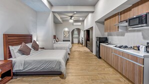 Una camera d'albergo moderna con angolo cottura, zona pranzo e corridoio che porta al bagno.