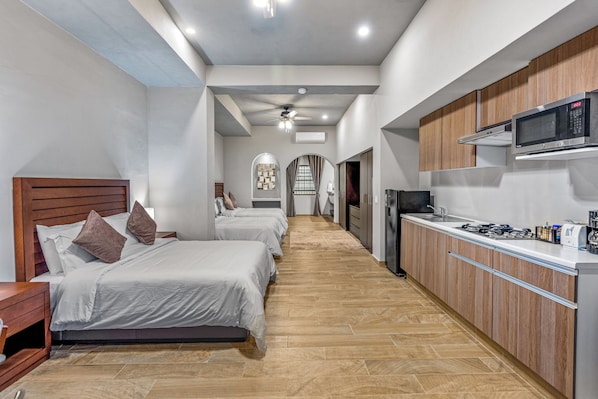 A modern hotel room with a kitchen area, a dining area, and a hallway leading to a bathroom. - Casa Cristal, Hotel Boutique (San Miguel de Allende)