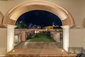 An outdoor dining area with a view of a cityscape at night, under a large archway. - Casa Cristal, Hotel Boutique (San Miguel de Allende)