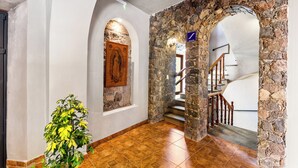 Un corridoio con pareti in pietra, una porta in legno e una scala che conduce a un altro piano.