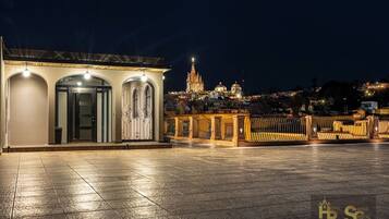 Un hotel con patio, vista a una catedral y balcón con barandilla.