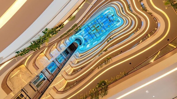Un moderno atrio de hotel con piscina central, varios niveles y un diseño curvo.