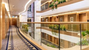 Un vestíbulo de hotel de varios niveles con techo curvo, barandales de vidrio y piso estampado.