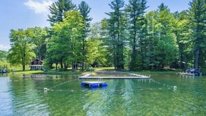A lake with a dock and a house in the background.