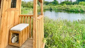 Eine Holzhütte mit Veranda mit Blick auf einen Fluss.
