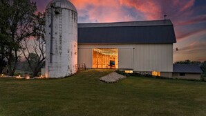 Ein Bauernhof mit einem großen Silo, einem überdachten Eingang und einem gut beleuchteten Innenraum.