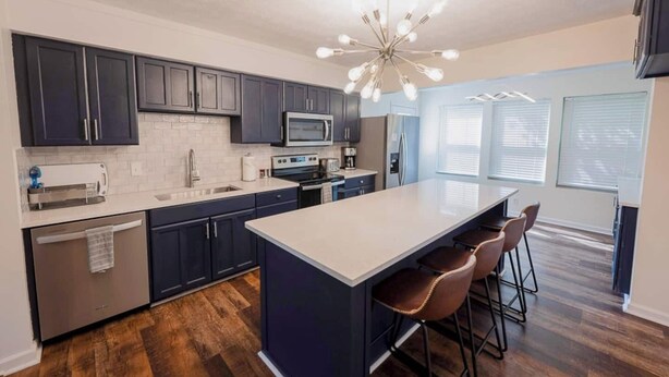 A modern kitchen with dark cabinets, a central island, and a bar area. - Game Room|Chef Kitchen|Dogs OK|1 mi to downtown GC (Grove City)