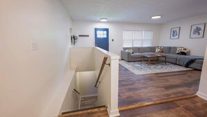 A staircase leading to a living room with a gray sofa, a coffee table, and a patterned rug. - Game Room|Chef Kitchen|Dogs OK|1 mi to downtown GC (Grove City)