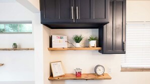 A kitchen with dark cabinets, wooden shelves, a thank you sign, potted plants, a framed menu, a no smoking sign, and a clock. - Game Room|Chef Kitchen|Dogs OK|1 mi to downtown GC (Grove City)