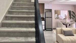 A modern interior with a staircase leading to a second floor, a dining area with a table and chairs, and a sofa with a patterned pillow. - Luxury Duplex -Marrakech Centre (Marrakech)