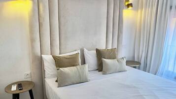A hotel room with a large bed, two bedside tables, and a headboard with built-in lighting.