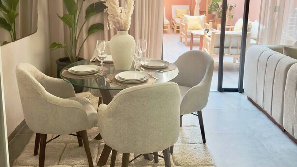 A dining area with a glass table, four chairs, and a vase with white flowers. - Luxury Duplex -Marrakech Centre (Marrakech)