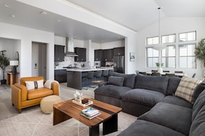 A modern living room with a sofa, a coffee table, and a dining area with chairs.