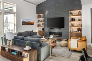 A modern living room with a fireplace, a flat-screen TV, and a bookshelf.