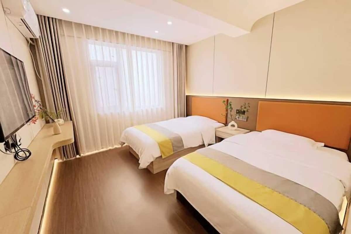 Une chambre d’hôtel avec deux lits, une table de chevet, un miroir et une fenêtre avec des rideaux.