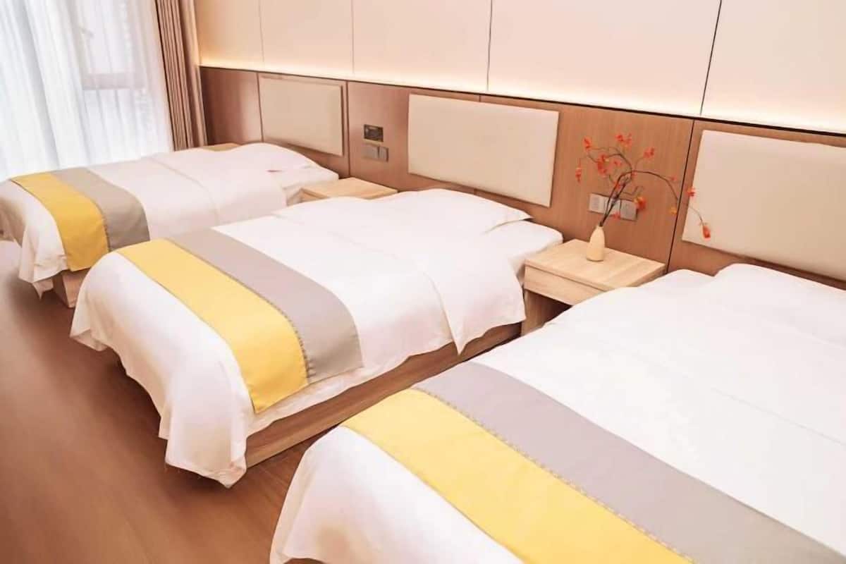 Une chambre d’hôtel avec deux lits, des têtes de lit en bois, des tables de chevet et un vase avec des fleurs.