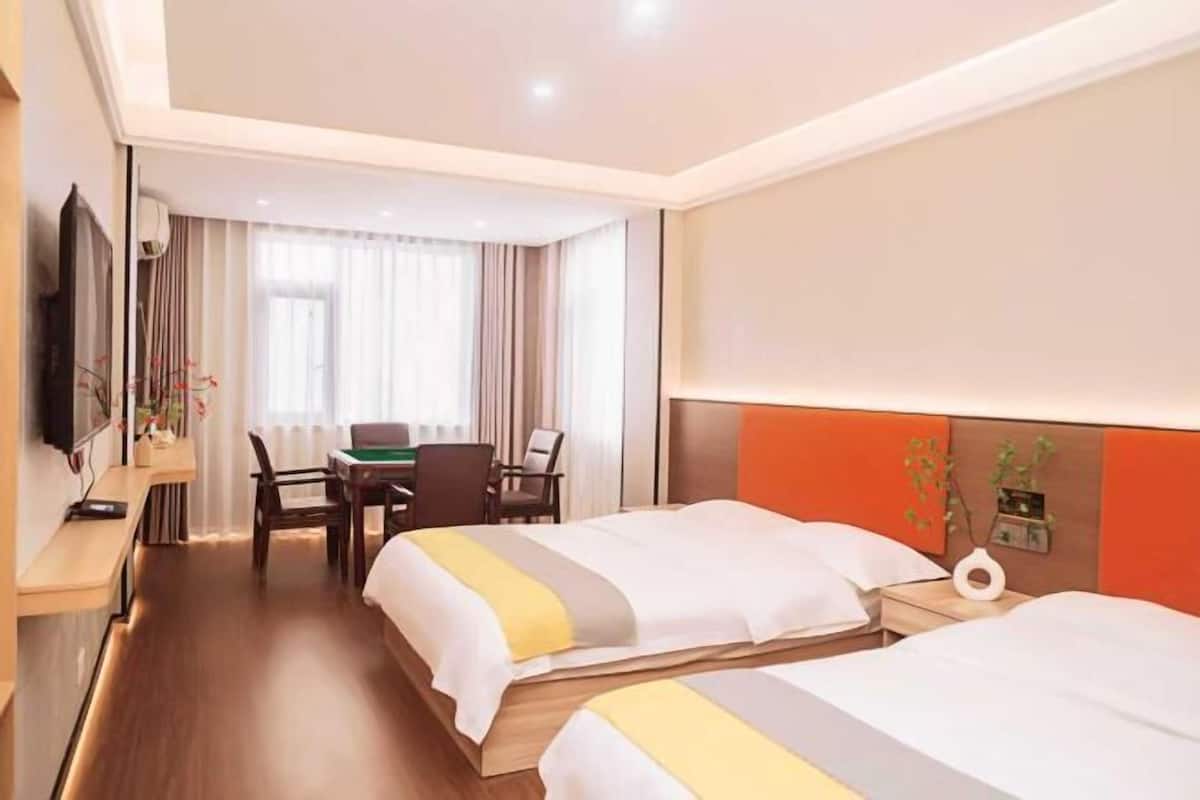 Une chambre d’hôtel avec deux lits, un bureau, une chaise, une télévision et une fenêtre avec des rideaux.