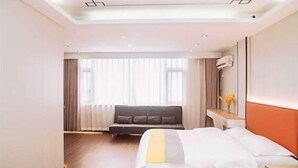 Une chambre d’hôtel avec un lit, un canapé, une table de chevet et une fenêtre avec des rideaux.