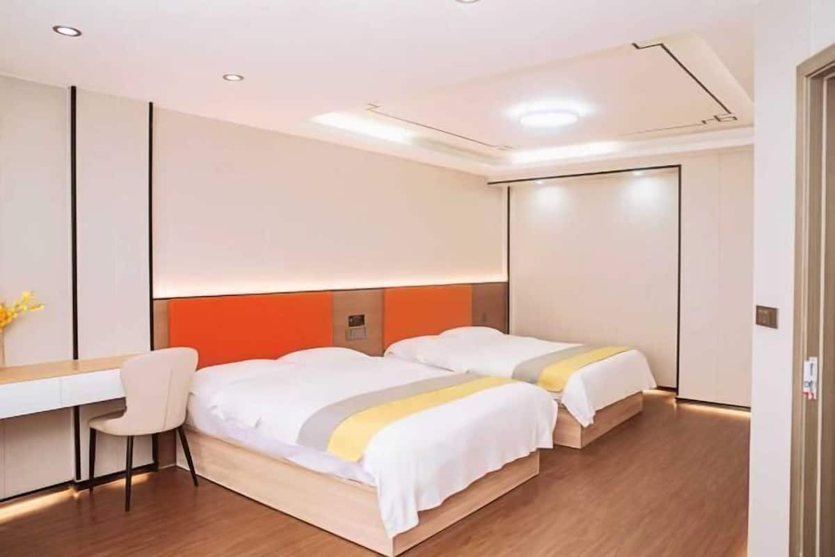 Une chambre d’hôtel moderne équipée d’un bureau, de deux lits et d’une chaise.