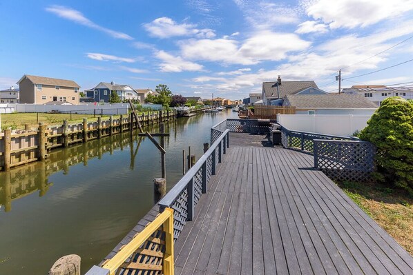 Un muelle de madera que conduce a una v ía fluvial tranquila, rodeado de edificios residenciales.