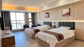 Habitación de hotel con dos camas, un escritorio y un ventanal grande.