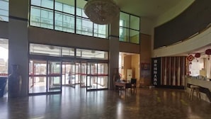Un vestíbulo espacioso con techo alto, ventanas amplias y una zona de estar central.