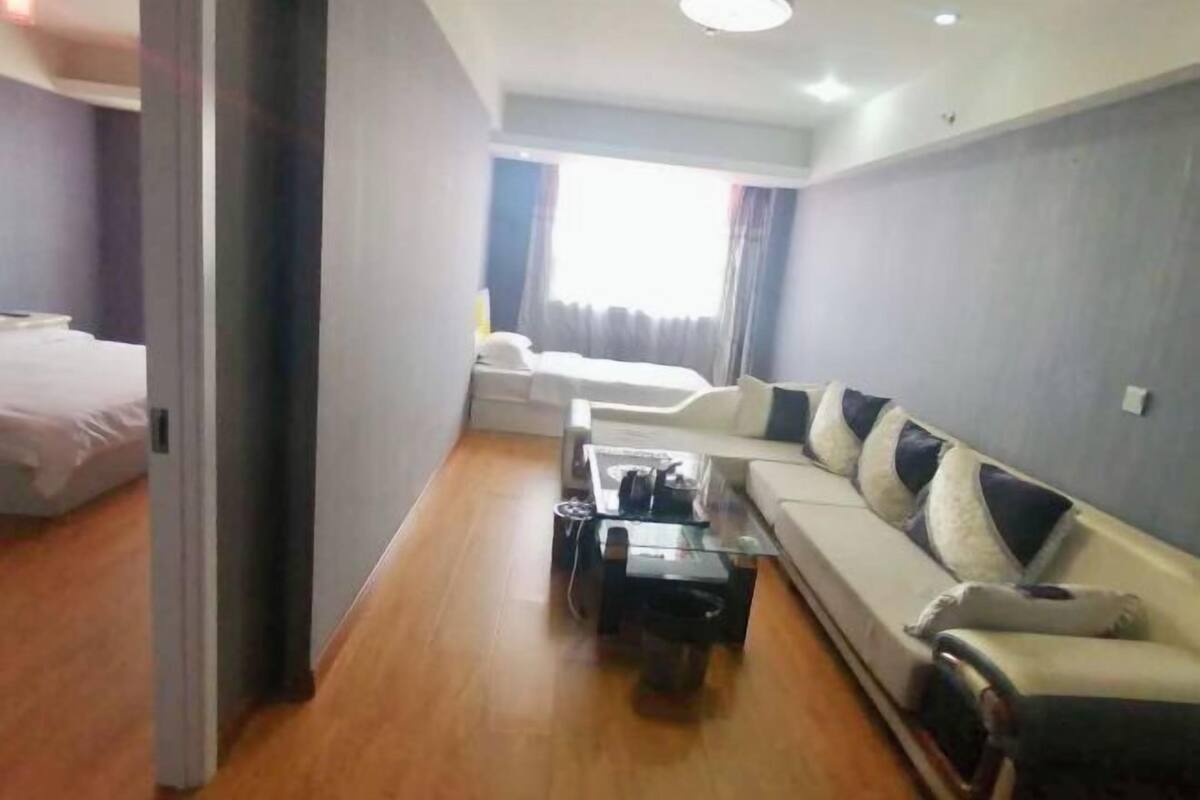 A modern hotel room with a sofa, a coffee table, and a bed.