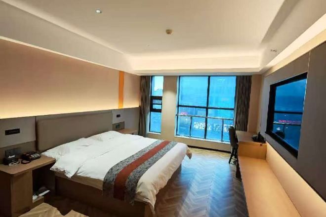Habitación de hotel con cama, mesita de noche, silla y un amplio ventanal con vistas.