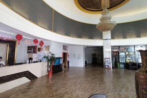 Een ruime lobby met een receptiebalie, een grote kroonluchter en een gebogen plafond.