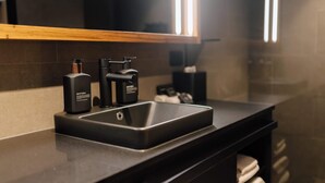 A modern bathroom with a black sink, a mirror, and a towel rack.