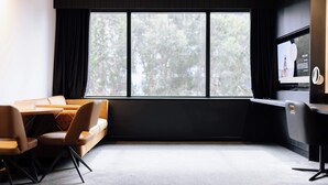 A modern conference room with a large window, a sofa, a table, and a TV screen displaying a welcome message. - One Bedroom Accessible In CBD (Newcastle)
