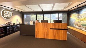 A modern reception desk with a wooden finish, a neon sign on the wall, and a cityscape mural. - Two Bedroom Interconnect Deluxe In CBD (Newcastlwe)