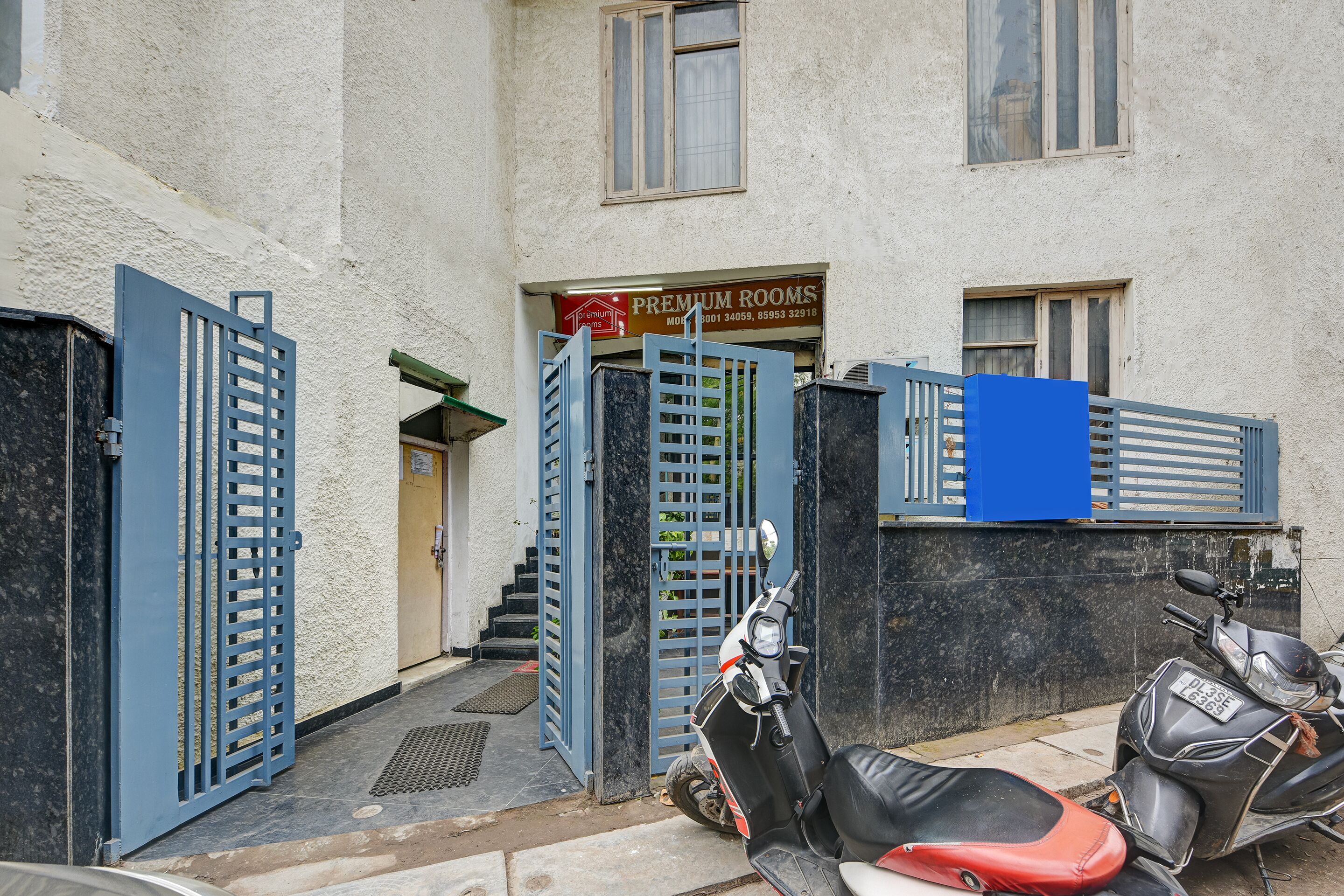 Un immeuble avec une enseigne indiquant « Chambres de luxe » et deux scooters garés devant.